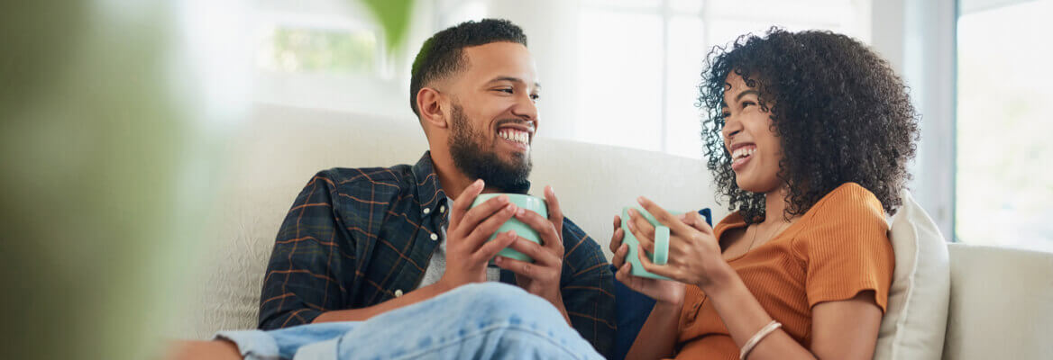 Couple sitting on living room couch drinking tea